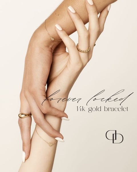 A close-up aesthetic shot of a model wearing minimalist gold rings and bracelets, emphasizing a high-end, clean brand image.