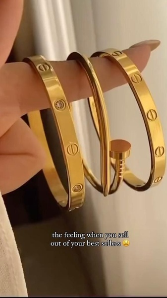 A close-up aesthetic shot of stacked gold bracelets featuring a text overlay about selling out of best sellers.