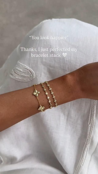 A 9:16 vertical social proof ad featuring a close-up of a three-piece jewelry stack with white linen clothing in the background.