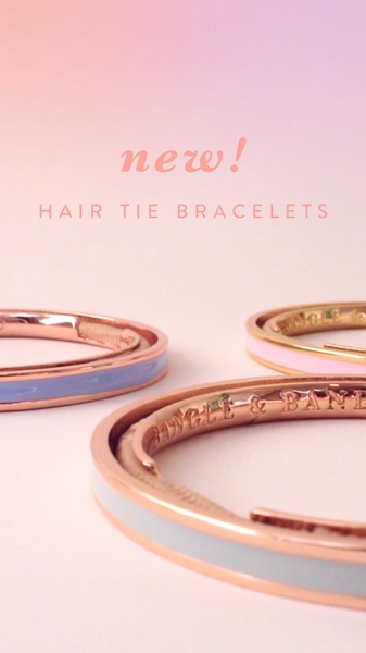 A clean, high-end product shot featuring three colorful hair tie bracelets displayed on a soft, pastel gradient background to announce a new arrival.
