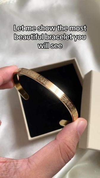 A close-up, high-quality shot of a gold bracelet held in hand against a soft, clean background to highlight its intricate details.