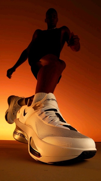A high-angle, extreme close-up shot of a white performance running shoe, captured with a dramatic orange-hued lighting profile.