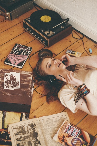 A high-angle lifestyle shot of a woman listening to a record player with vintage-style headphones, creating a warm, nostalgic mood.