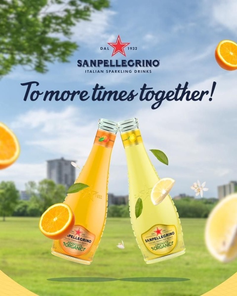 A 4:5 ratio ad creative showing two sparkling drink bottles clinking together in a sunny, outdoor park setting to evoke a feeling of shared moments.