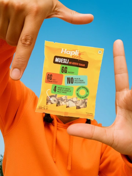 A bright, high-energy shot of a Muesli packet being held in a hand-frame against a vibrant blue background to isolate the key health benefits.