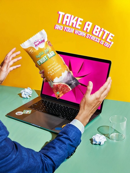 A high-contrast visual showing a hand grabbing a Fig and Honey Ice Cream bar through a laptop screen, framed by paper scraps and a vibrant yellow background.