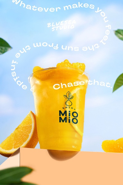 A high-quality product shot of an orange juice cup surrounded by orange slices, using warm, sun-drenched lighting and circular text design.