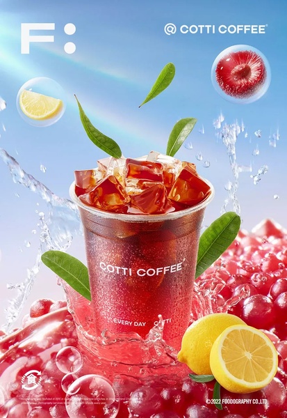 A high-energy, refreshing product hero shot of iced coffee featuring vibrant fruit elements and dynamic water splashes against a clear sky background.