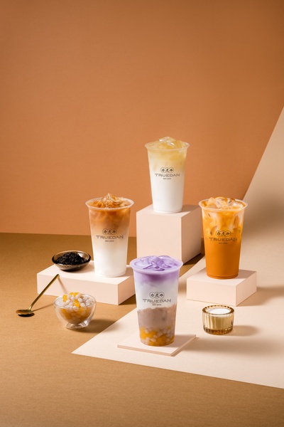 A high-end, studio-style product shot featuring four distinct bubble tea variations arranged on pedestals with elegant lighting.