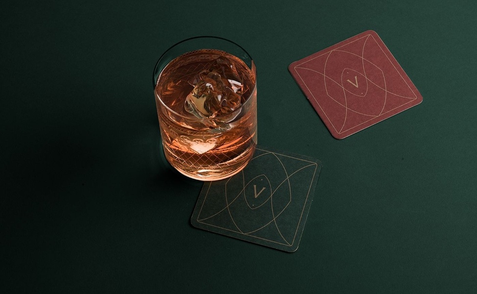 A high-contrast hero shot of a whiskey glass on a dark surface, featuring two minimalist coasters to create a premium, intimate atmosphere.