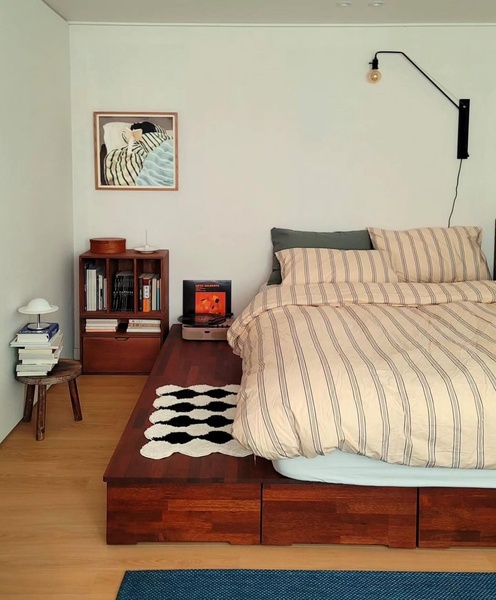 A high-quality, static lifestyle photograph featuring a wood platform bed in a minimalist bedroom setting, emphasizing a clean, aspirational aesthetic.