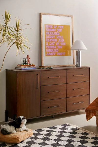 A dresser featured in a warm, relatable bedroom setting paired with aspirational wall art and decor.