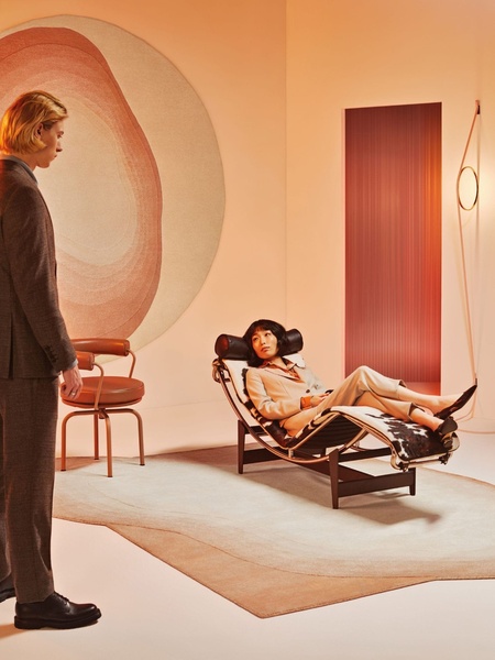 A high-end lounge chair is featured in a minimalist, warm-toned interior, emphasizing luxury and artistic composition rather than standard functional copy.