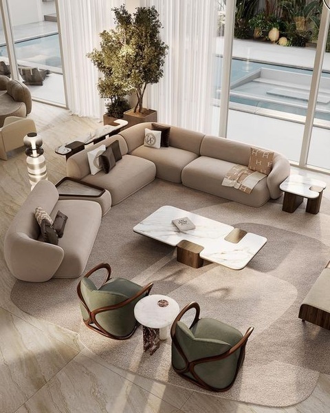 A high-angle interior shot showcasing a curved, neutral-toned sectional sofa set in an expansive, sunlit luxury living space.