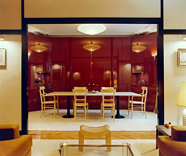 A high-end dining table setup featuring deep red wall paneling, symmetrical lighting, and a refined, minimalist aesthetic.