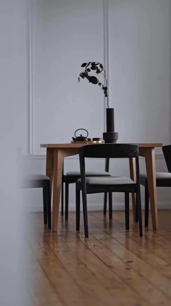 A high-end dining chair staged in a clean, neutral-toned interior with soft lighting and deliberate styling elements.