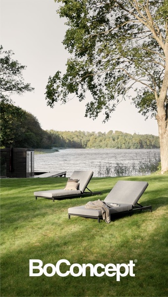 This creative showcases two minimalist sun loungers placed in an expansive, tranquil lakeside lawn setting to evoke a premium, aspirational lifestyle.