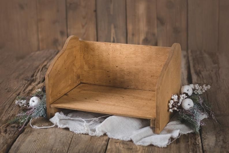 A high-quality wooden bench designed as a photography prop for newborn portraits, styled with seasonal greenery and winter-inspired decor.
