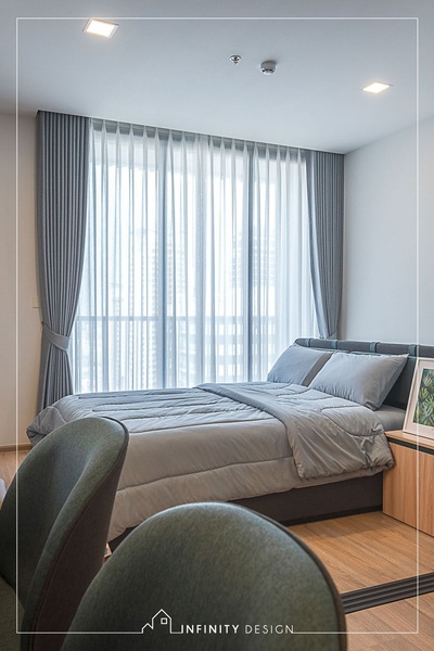 A high-quality, professional photograph showcasing floor-to-ceiling sheer curtains in a neutral-toned, modern bedroom setting.