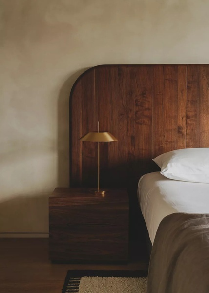 This creative showcases a high-quality wooden headboard in a warm, dimly lit bedroom, emphasizing texture and premium craftsmanship through a 3:4 portrait crop.