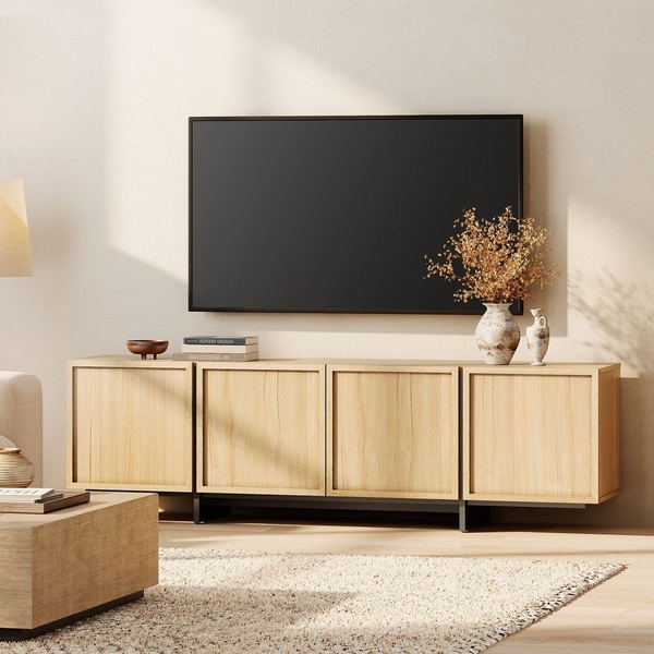 A clean, studio-lit photograph of a light wood media console positioned beneath a mounted television, featuring minimalist decor and a warm, airy atmosphere.