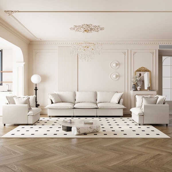 A professionally staged 1:1 image featuring a cream-colored sectional sofa in a bright, neutral, and elegant living space.