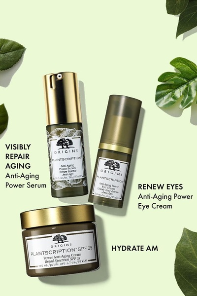 A flat-lay product shot of three anti-aging skincare products arranged symmetrically on a light green background with organic leaves.