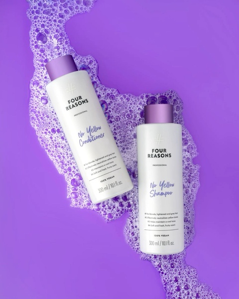 A high-contrast, overhead studio shot featuring purple shampoo and conditioner bottles resting in a vibrant purple foam bath.