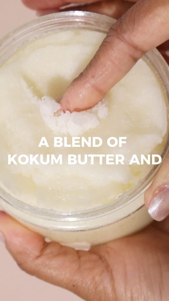 A close-up, tactile demonstration of kokum butter being pressed by a finger, emphasizing the product's rich and smooth texture.
