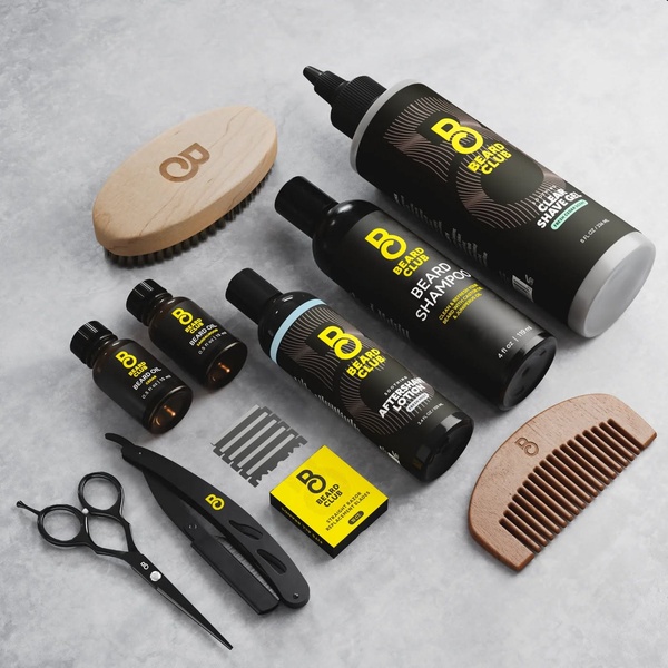 A high-end, top-down studio shot displaying a complete beard grooming collection including brushes, oils, and shaving tools against a clean grey surface.