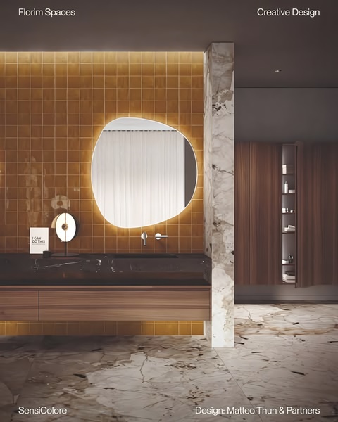 A high-end interior design shot featuring warm-toned ceramic tiles and a sculptural mirror in a modern, luxury bathroom setting.