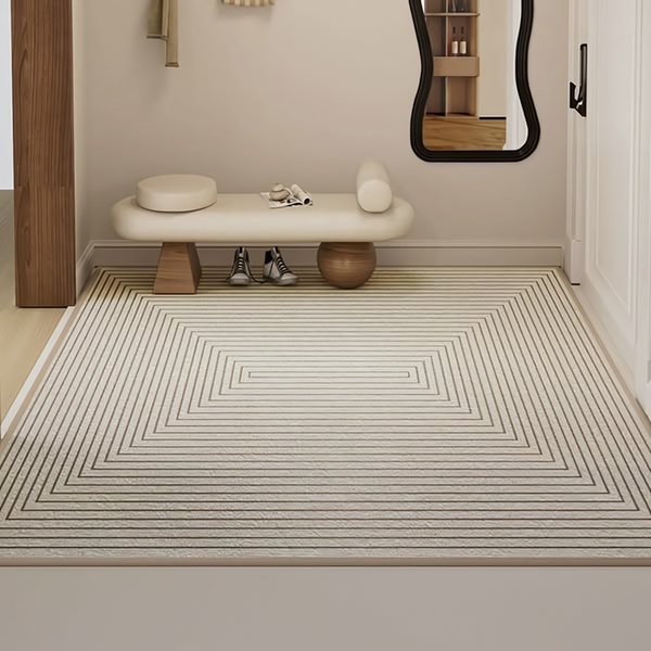 A high-angle, clean shot of a modern area rug in a neutral-toned entryway, focusing on geometric line patterns.