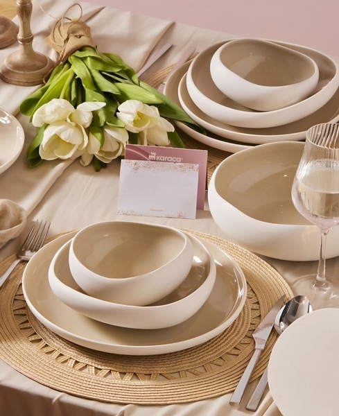 A sophisticated, high-end photograph of a dinnerware set placed on a table with fresh white tulips, emphasizing luxury and home lifestyle.