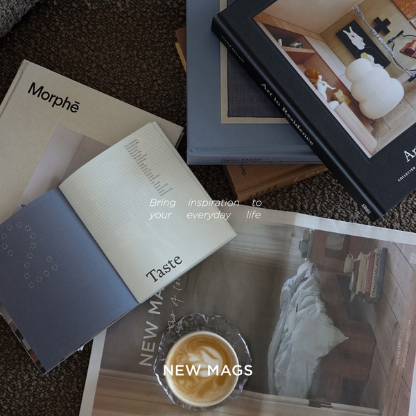 A high-angle flat lay featuring an open coffee table book, stacks of literature, and a fresh latte, emphasizing a calm and sophisticated reading experience.