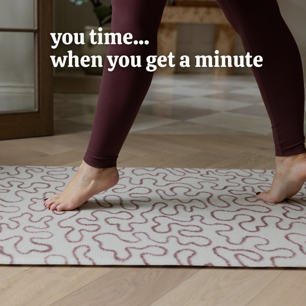 A close-up shot of feet on a patterned yoga mat with centered, aspirational text about finding personal time.