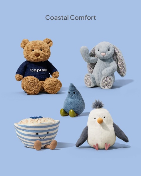 A clean, studio-lit display of diverse plush toys arranged against a soft blue backdrop to evoke a calm, coastal aesthetic.