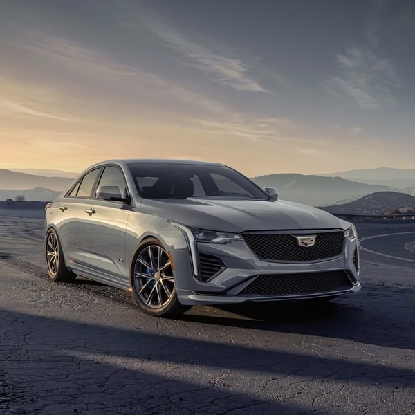 A high-end sedan parked on a winding mountain road during sunset, emphasizing its sleek lines and premium design.