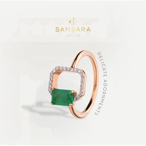 A refined product hero shot featuring a gold and emerald ring centered against a clean, architectural background to emphasize luxury.