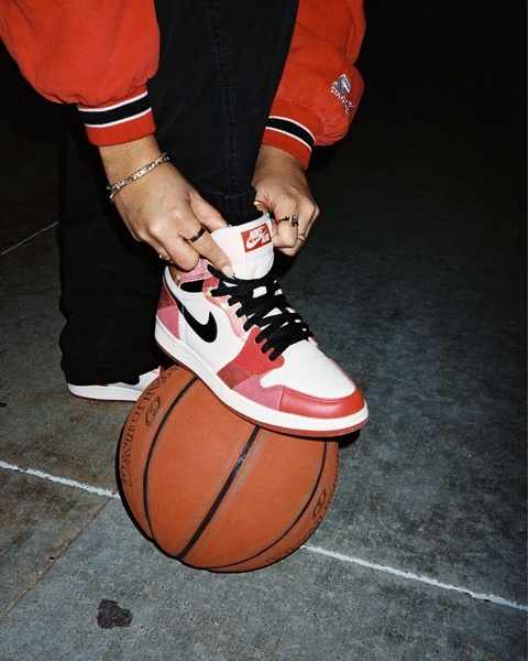 A close-up, high-contrast lifestyle shot focusing on a pair of basketball sneakers resting on a basketball, capturing an authentic urban streetwear vibe.