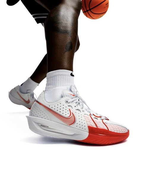 A high-contrast, isolated product shot of a basketball sneaker worn in action, set against a stark white background.