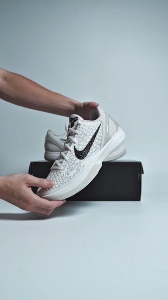 A close-up, high-quality shot of a person holding a minimalist basketball shoe against a neutral background, focusing on the texture and design.