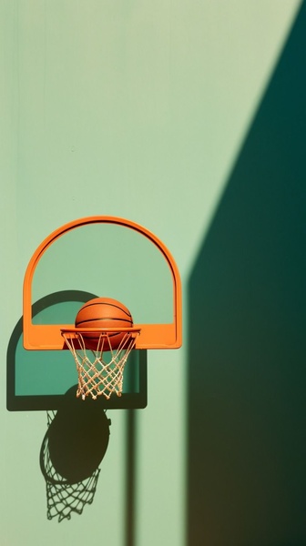 A high-contrast, artistic photograph of a basketball hoop against a solid green background, focusing on negative space and clean geometry.