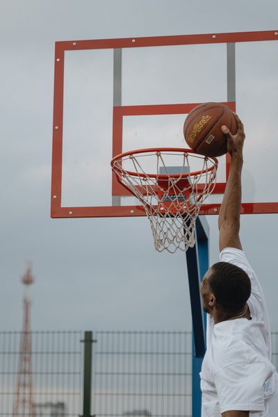 A dynamic shot showing a basketball player mid-dunk, capturing the peak of the action from a low-angle perspective.
