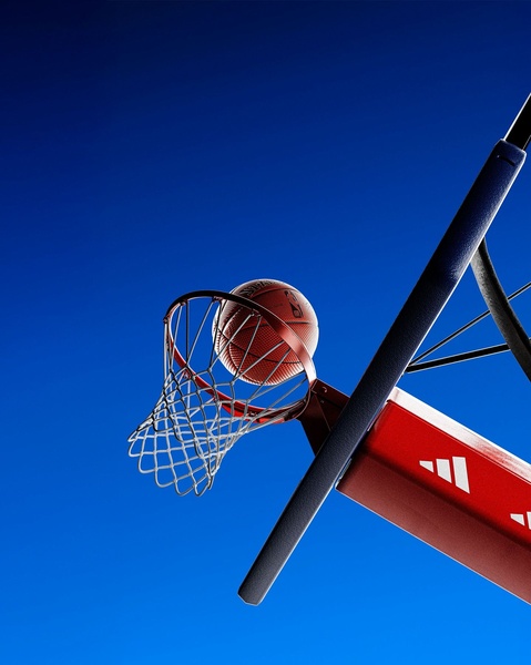 A high-contrast, low-angle shot of a basketball entering a net against a clear blue sky, emphasizing the product with bold red and blue colors.