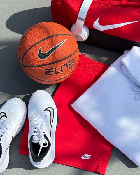 A high-angle flat lay shot showcasing a basketball, gym bag, sneakers, and clothing on a clean, neutral surface.