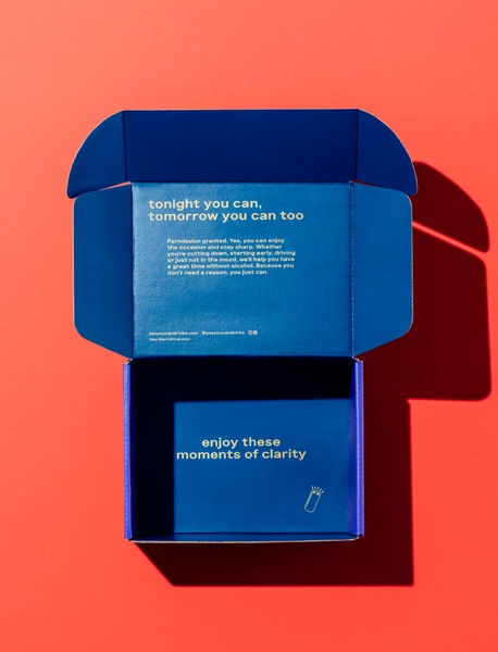 A high-contrast, overhead shot of an open, branded blue delivery box against a red background, featuring text that highlights moments of clarity.