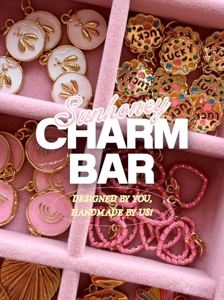 A top-down view of a velvet jewelry organizer filled with various gold and enamel charms, highlighting the customization options.