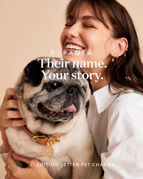 A heartfelt, high-key portrait showing a smiling woman holding her dog, highlighting a gold initial charm on the dog's collar to emphasize personal connection.