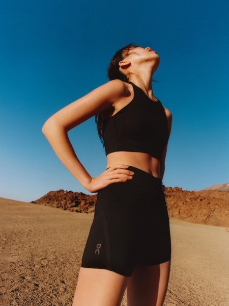 A high-quality lifestyle portrait of a runner wearing a black sports bra in an outdoor desert environment.