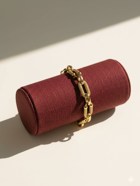 A high-end, clean studio shot of a gold chain bracelet resting on a cylindrical display stand.